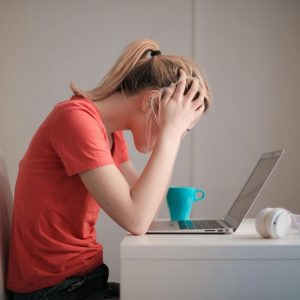 woman in red t shirt looking at her laptop